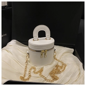 Detail of white mini cylinder bag with gold zippers in a premium satin-lined gift box
