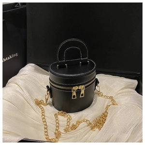 Close-up of black cylinder handbag on white silk with golden chain and zip detail