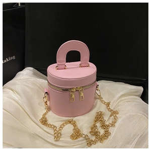 Macro shot of pink cylindrical leather handbag with double gold zippers and chain strap