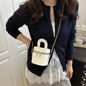Asian model carrying a white mini cylinder bag with gold chain and dual zippers