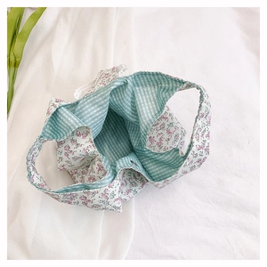 Detail of floral tote bag with white lace trim and green gingham lining fabric