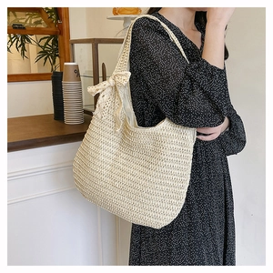 Gros plan du sac cabas en crochet beige avec nœud en dentelle délicate sur la sangle