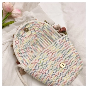Détail d'un sac bandoulière tissé avec broderie ondulée colorée et accents de pompons roses