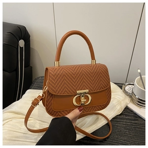 Détail du rabat tissé et de la boucle métallique dorée en D sur le sac à main marron