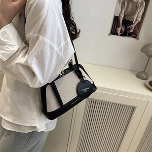 Chic canvas and leather contrast shell tote bag with fashion text for summer 2025 style