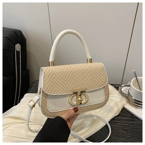 Détail de la boucle CD dorée sur sac à main bicolore en paille et cuir blanc