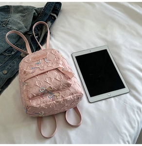 Macro detail of pink quilted PU backpack with colorful bow embroidery and zipper pocket