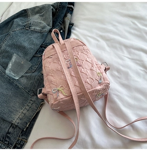 Detailed macro of pink PU leather mini backpack with quilted pattern and colorful bows