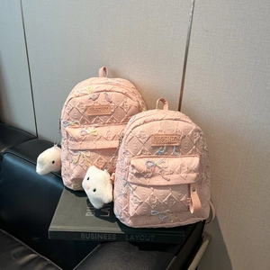 Detailed view of pink quilted backpacks with sequin bows and cute plush cat charms