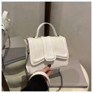 Detail shot of white crocodile embossed leather handbag with metallic chain strap