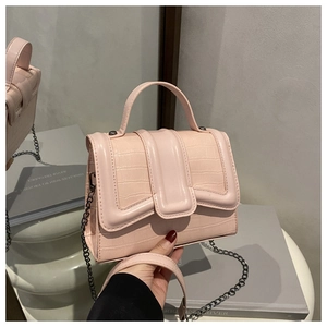 Detail of pink crocodile embossed leather bag with metal chain and wide shoulder strap