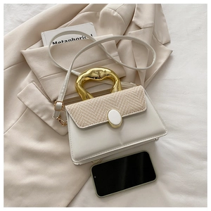 Detail of minimalist cream leather handbag with woven flap and wavy gold handle