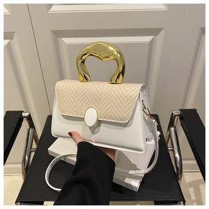 Detail of white leather bag with straw flap and unique gold metal handle