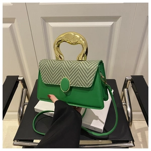 Detail of green leather and fabric handbag featuring a unique gold metal handle