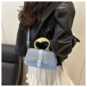 Detail of light blue crossbody bag with gold H-buckle and metal handle on model