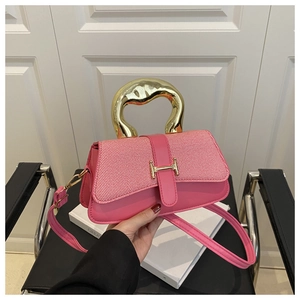 Borsa rosa con manico curvo in metallo dorato e fibbia ad H mostrata a mano
