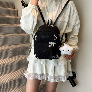 Black school backpack with butterfly embroidery and star pendant shown on model