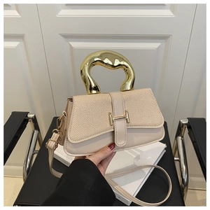 Dettaglio della borsa beige con fibbia a H dorata e manico in metallo dal design ondulato