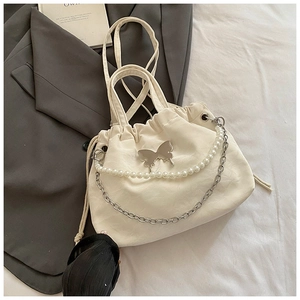 Detail of white drawstring bag featuring silver butterfly buckle and pearl chain deco