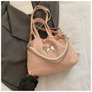 Detailed view of pink pleated handbag featuring silver butterfly and pearl chain