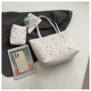 Dettaglio della borsa tote bianca con fiocchi rosa e fiori accanto a tablet e smartphone