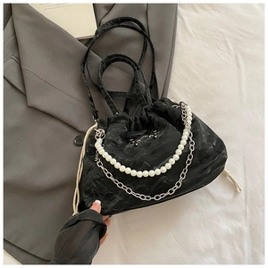 Detail of black drawstring bucket bag with decorative pearl and silver metal chains