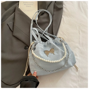 Detail of light blue drawstring bag with silver butterfly charm and pearl chain handle