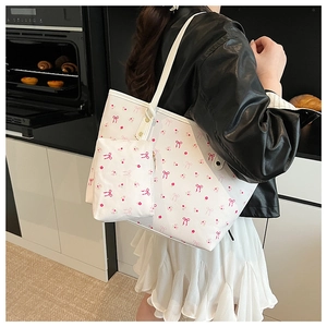 Dettaglio del set borsa tote bianca con motivi a fiocco rosa e pochette portaoggetti abbinata