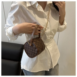 Détail du sac bandoulière cylindre marron avec motif monogramme et chaîne dorée