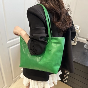 Green faux leather tote bag with crocodile texture on woman in black blazer