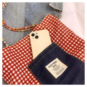Dettaglio della borsa tote a quadretti rossi con tasca in denim e corde colorate