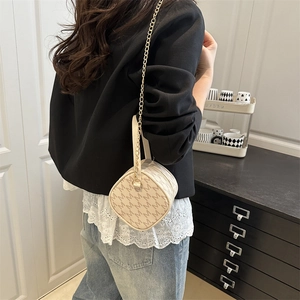 Sac cylindre beige avec imprimé monogramme et bandoulière chaîne dorée élégante