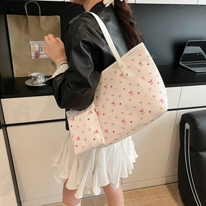 Set borsa tote floreale con fiocchi rosa su pelle color crema in scena urbana