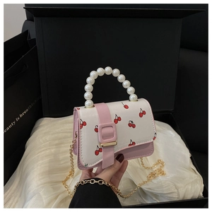 Detailed view of pearl handle and cherry print on pink mini crossbody bag in gift box