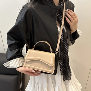 Minimalist beige leather handbag with wave stitching and shoulder strap on model
