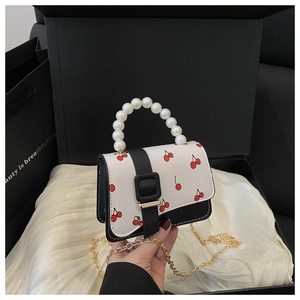 Detailed close-up of cherry print mini bag with pearl handle and golden chain strap