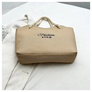 Détail du sac cabas beige avec texture sergé, poignées en corde et broderie noire