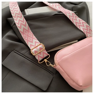 Pink square bag with patterned wide strap over a dark blazer for a stylish look