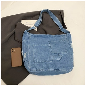 Detail of blue denim tote bag showing multi-pocket design and stylish frayed edge texture