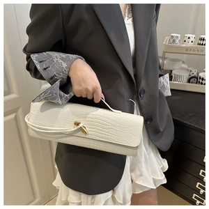 Close-up of white croc-embossed handbag with gold metal twist lock on a model