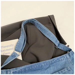 Detail of wide denim shoulder strap and metal ring buckle on blue tote bag