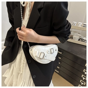 Détail du sac bandoulière blanc en forme de cœur avec chaîne et boucles métalliques