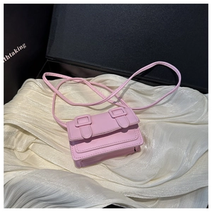 Detail of pink mini crossbody bag featuring dual square buckles and a matte PU finish
