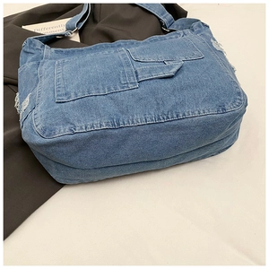 Detail of blue denim tote bag featuring vintage cargo pockets and distressed frayed edges