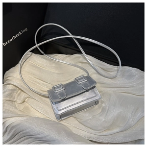 Detailed close-up of a mini silver metallic crossbody bag with dual square buckles