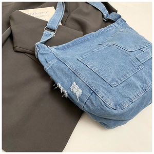 Detailed close-up of light blue washed denim bag with frayed edges and utility pockets
