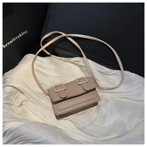 Detail view of khaki mini square bag with dual square buckles on textured white silk