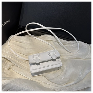 Detailed close-up of a white mini square crossbody bag with double buckle straps