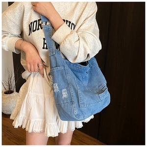 Close-up of vintage blue denim tote bag with stylish distressed edges and pocket details