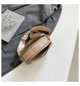 Detail view of beige crossbody bag with double zippers and wide fabric shoulder strap